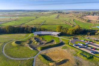 A contemporary visitor centre building sits within the vast green landscape of marshes and wildlife habitat.