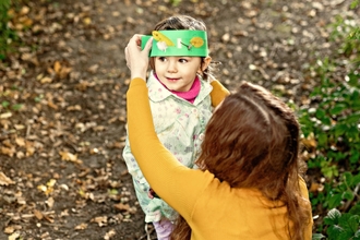 Person holding a leaf crown on a child's head