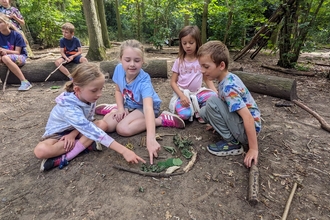 Children sitting on the floor playing with leaves