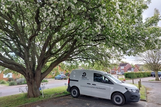 Suffolk Wildlife Trust's electric van parked under the blossoming cherry tree