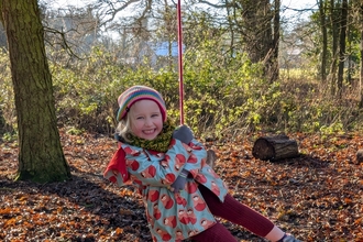 Girl on rope swing in woods 