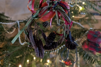 Willow and cone christmas decoration hanging on a fir tree with lights in the background