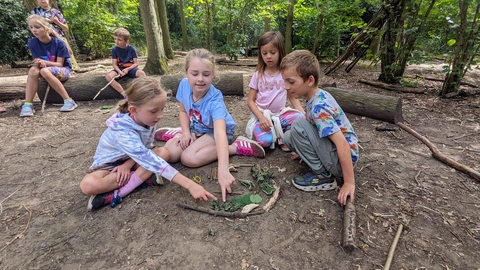 Children sitting on the floor playing with leaves