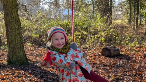 Girl on rope swing in woods 