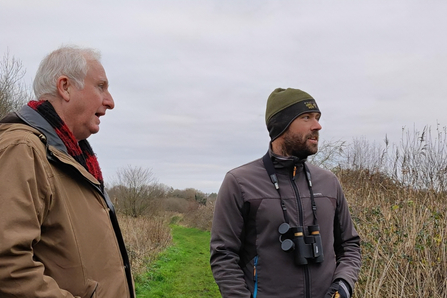 Two people talking whilst overlooking a wild landscape